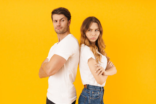 Portrait of serious offended couple man and woman in basic t-shirts standing back to back with arms folded in quarrel