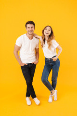 Fototapeta na wymiar Full length portrait of beautiful couple man and woman in basic t-shirts standing together and laughing at camera
