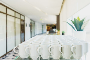 Stack of clean dishes plates and cups on a table prepared by the catering service for the event. 