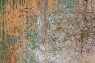 old shabby white yellow concrete wall with cracks, deep scratches and stains of green paint and dirt. rough surface texture