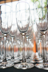 Several rows clear transparent, clean glasses for wine and champagne on counter prepared for drinks.