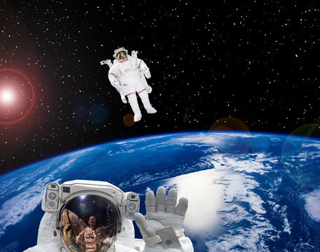 Earth and astronauts in space suits in outer space. Space walk. The elements of this image furnished by NASA.