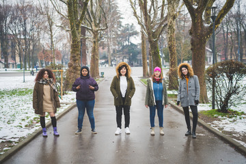 group of young multiracial women posing in tree lined avenue
