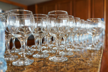 Several rows clear transparent, clean glasses for wine and champagne on counter prepared for drinks.