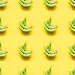 Sweet fresh green banana on punchy pastel yellow background. Top view. Seamless pattern.