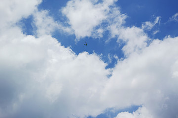 白い雲と青空の間を飛ぶ小型飛行機