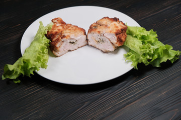 Cutlet of poultry meat on the kitchen table. Russian national dish of chicken Kiev. Stuffed chicken cutlet with lettuce leaves.
