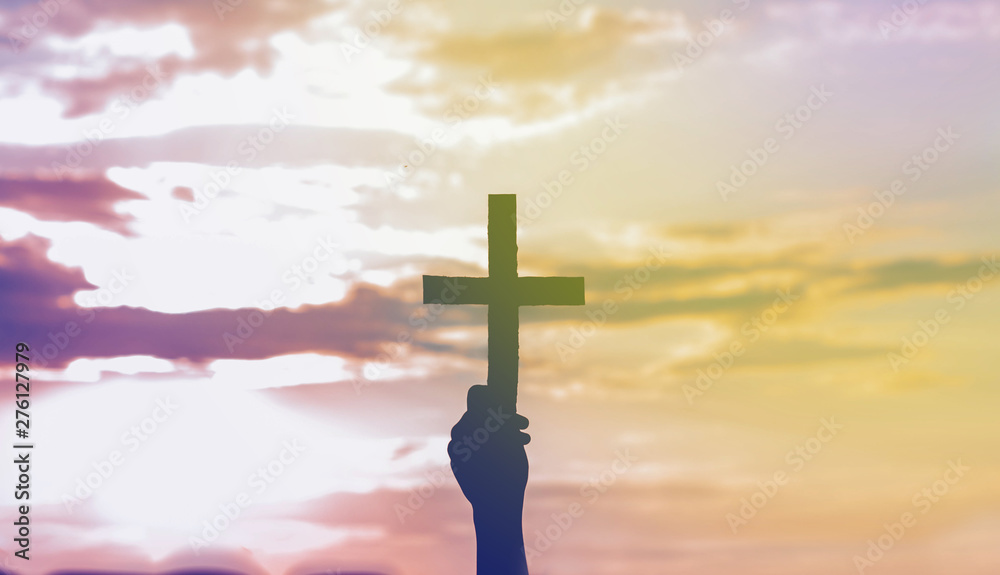 Wall mural teenager girl holding a the cross in hand during beautiful sunset. hands folded in prayer concept fo