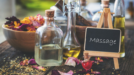 Schild mit Ölen und Rosenblütenblättern: massage
