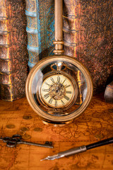 Antique clock on the background of a magnifying glass and books. Vintage style. 1565 old map of the year.