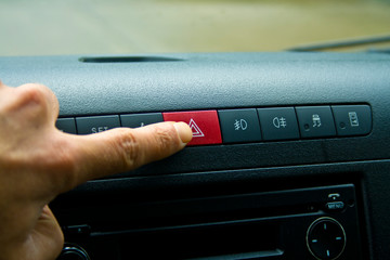 Finger hitting car emergency red light button in the car.