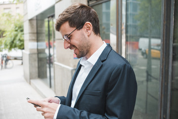 Fototapeta premium Smiling young businessman using smartphone