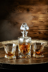 A bottle of cognac and glass on a brown wooden background. Brandy