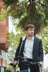 Portrait of a young businessman with his bicycle looking away