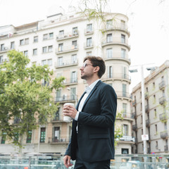 Young businessman standing in front of building holding coffee cup in hand