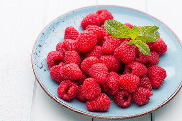 Fresh raspberries in a plate on a  vintage background.