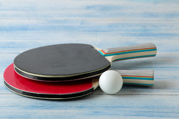 Two ping pong rackets. Table tennis rackets and a ball on a blue wooden table. sport game.