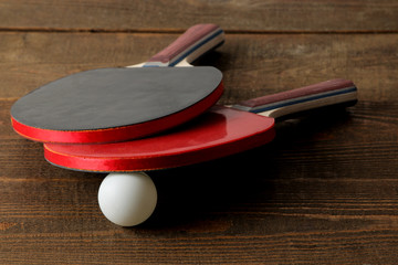 Two ping pong rackets. Table tennis rackets and a ball on a brown wooden table. sport game.