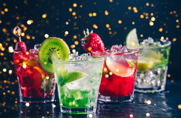 Four colorful tasty alcoholic cocktails in a row at the bar stand. Luxury vacation concept. Toned...