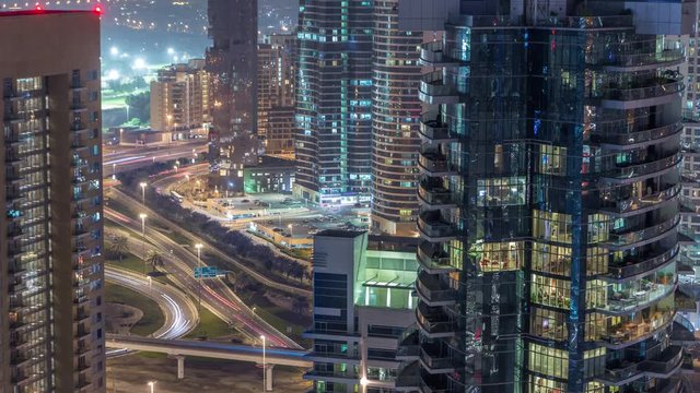 Aerial view of a road intersection in a big city night timelapse. Urban landscape of Dubai Marina and JLT district in UAE with cars and metro