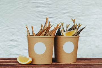 grilled sea fish with lemon wedges street food in box on wooden background