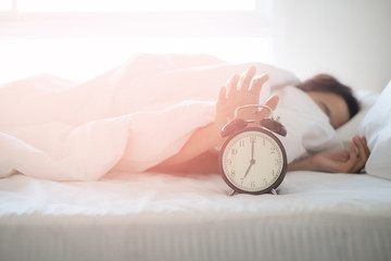 Woman sleep on the bed turns off the alarm clock wake up at the morning, Selective focus.