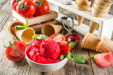 Vegetable gelato. Tomato ice cream with fresh tomatoes and basil and leaves, old rustic wooden background.