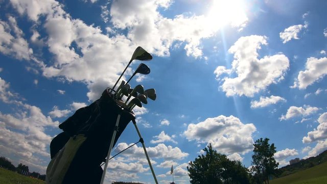 Timelapse of moving clouds and a stack of golf clubs
