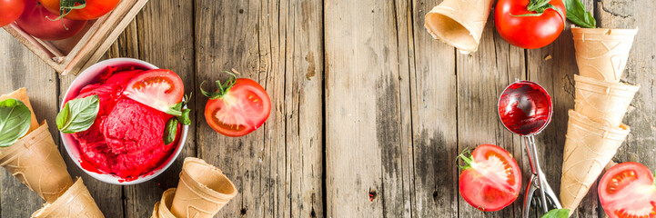 Vegetable gelato. Tomato ice cream with fresh tomatoes and basil and leaves, old rustic wooden background.