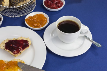 breakfast table with freshly baked heart shaped buns, different jams and coffee