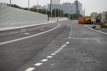 The texture of gray asphalt road. White markings on the track. Road trip. Big wide road.