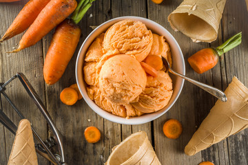 Vegetable gelato. Vegan carrot ice cream with organic baby carrots, old rustic wooden background.