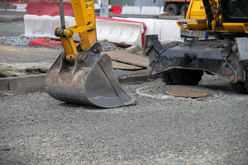 Excavator bucket digging ground for installing pipes at the street