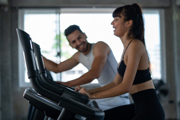 Fototapeta premium Defocused blurred medium shot of active man and woman smiling while doing aerobic cardio workout on training exercise bike at the fitness gym. Healthy weight loss fit and firm concept.