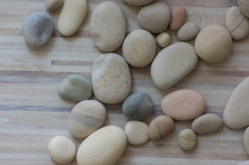Group of white, grey and light brown stones on white light wooden background, pebbles beach