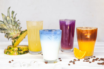 assortment of fresh iced fruit drinks on a white background with chopped slices of pineapple and orange, closeup