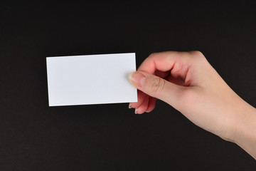 Empty card in woman hand  on a black background.