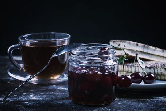 Cherry jam and tea on a wooden table
