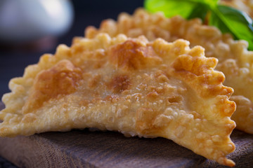 Chebureki - pan fried pies with meat and onions, served on wooden board. Fried-dough food