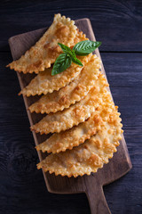 Chebureki - pan fried pies with meat and onions, served on wooden board. Fried-dough food