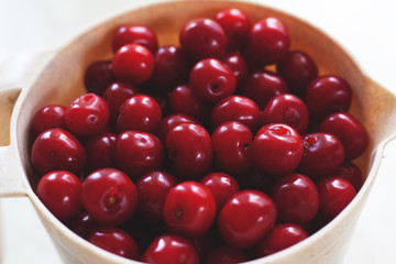 fresh picked red cherry in a large plastic cup on a light background 