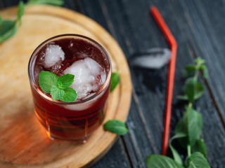 Red cocktail with ice and mint close-up