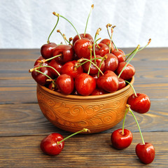 Sweet cherry berries in a clay pot on a wooden table. Side view