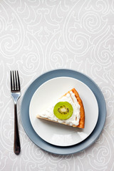 Homemade cottage cheese cake with kiwi fruit and cream on a plate