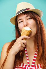 Woman wearing a a swimsuit and straw hat eats icecream from cup over colorful turquoise background