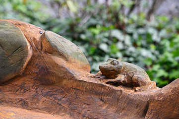 A frog carved on a trunk of wood.