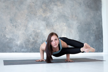 Fototapeta na wymiar Young european woman with long hair holding arm balance in Astavakrasana yoga pose. Full length studio shot