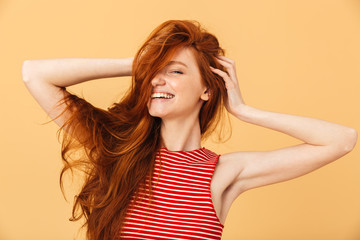 Fototapeta premium Excited happy emotional young beautiful redhead woman posing isolated over yellow background.