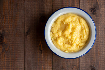 Basic polenta in a bowl on a wooden background, top view. Traditional Italian food, vegan food.