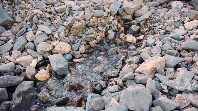 The water flow breaks out from under the stones.